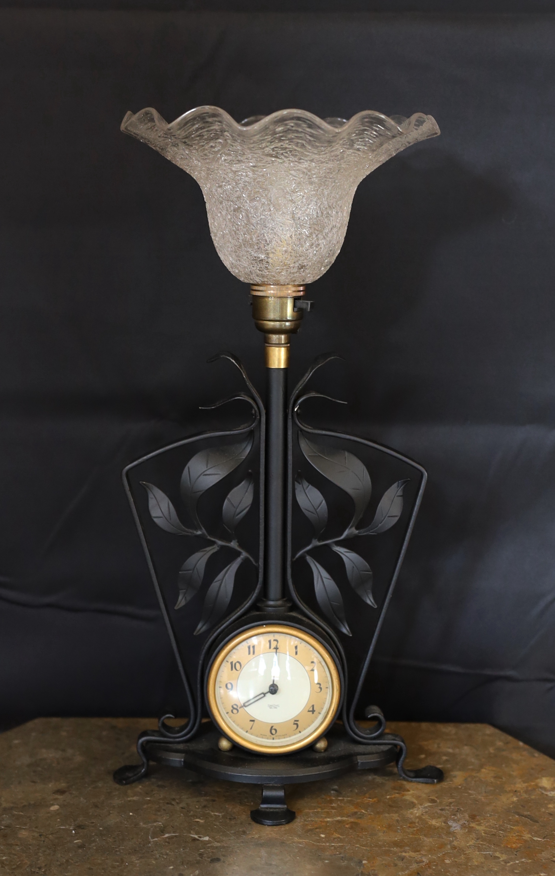 A 1930s English wrought iron table lamp inset with a Smiths Sectric timepiece, height overall 40cm